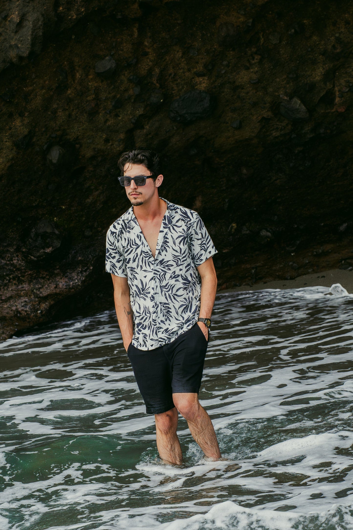 Man wearing Borneo Bliss Velvet Noir sunglasses standing in the sea in Bali