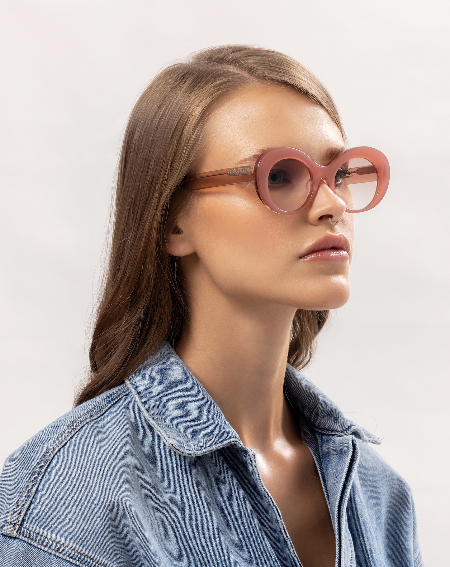 Light-tinted pink sunglasses softly presented on a woman relaxing inside a Bali villa, adjusted by skilled optometrists.