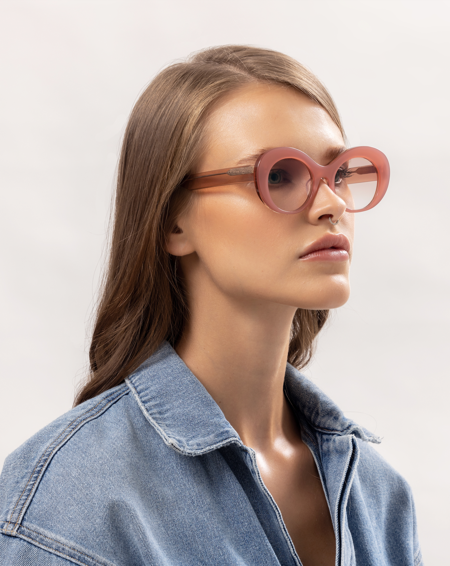 Light-tinted pink sunglasses softly presented on a woman relaxing inside a Bali villa, adjusted by skilled optometrists.