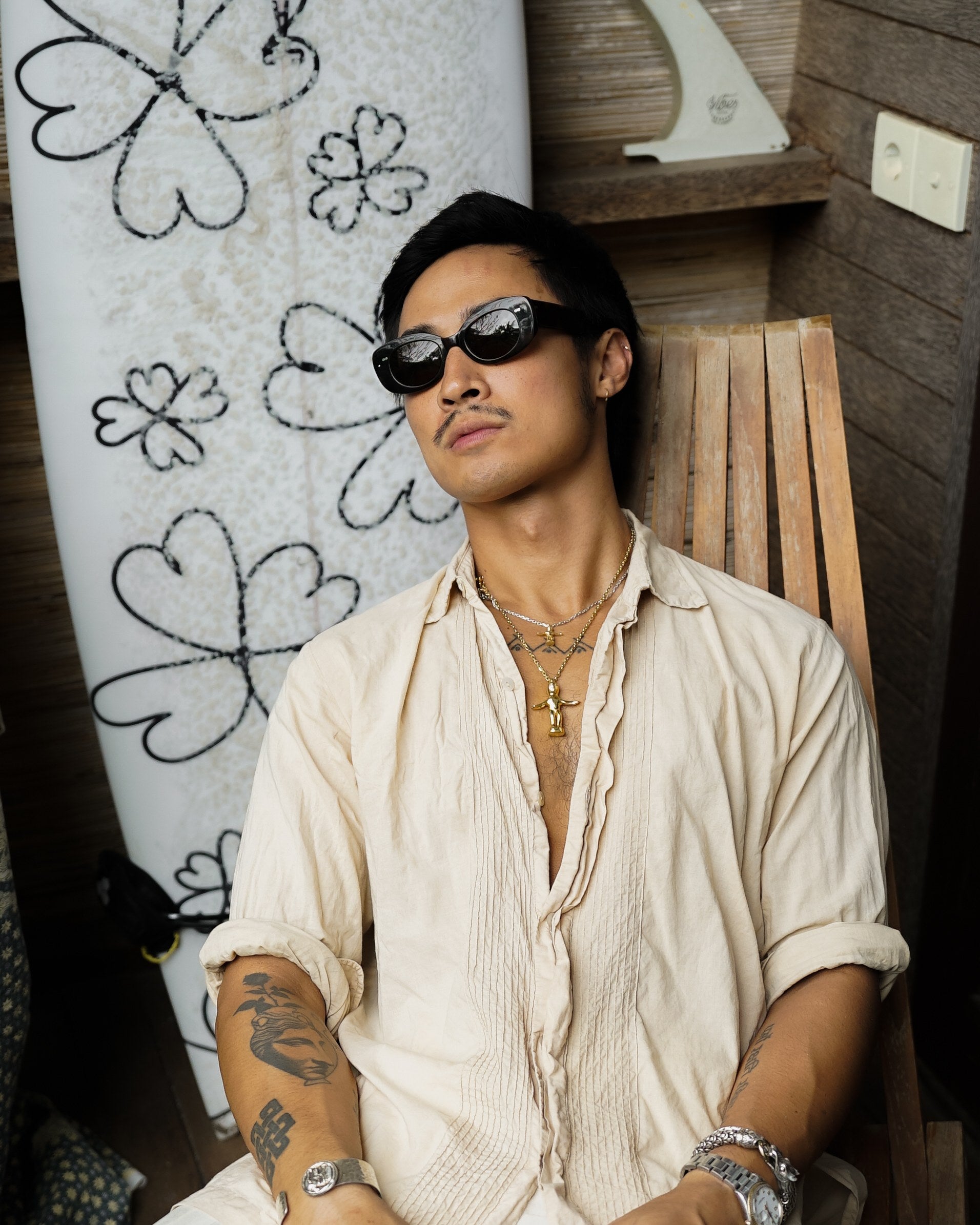 Man in Bali Blue Midnight Sky sunglasses leaning against surfboards in Bali