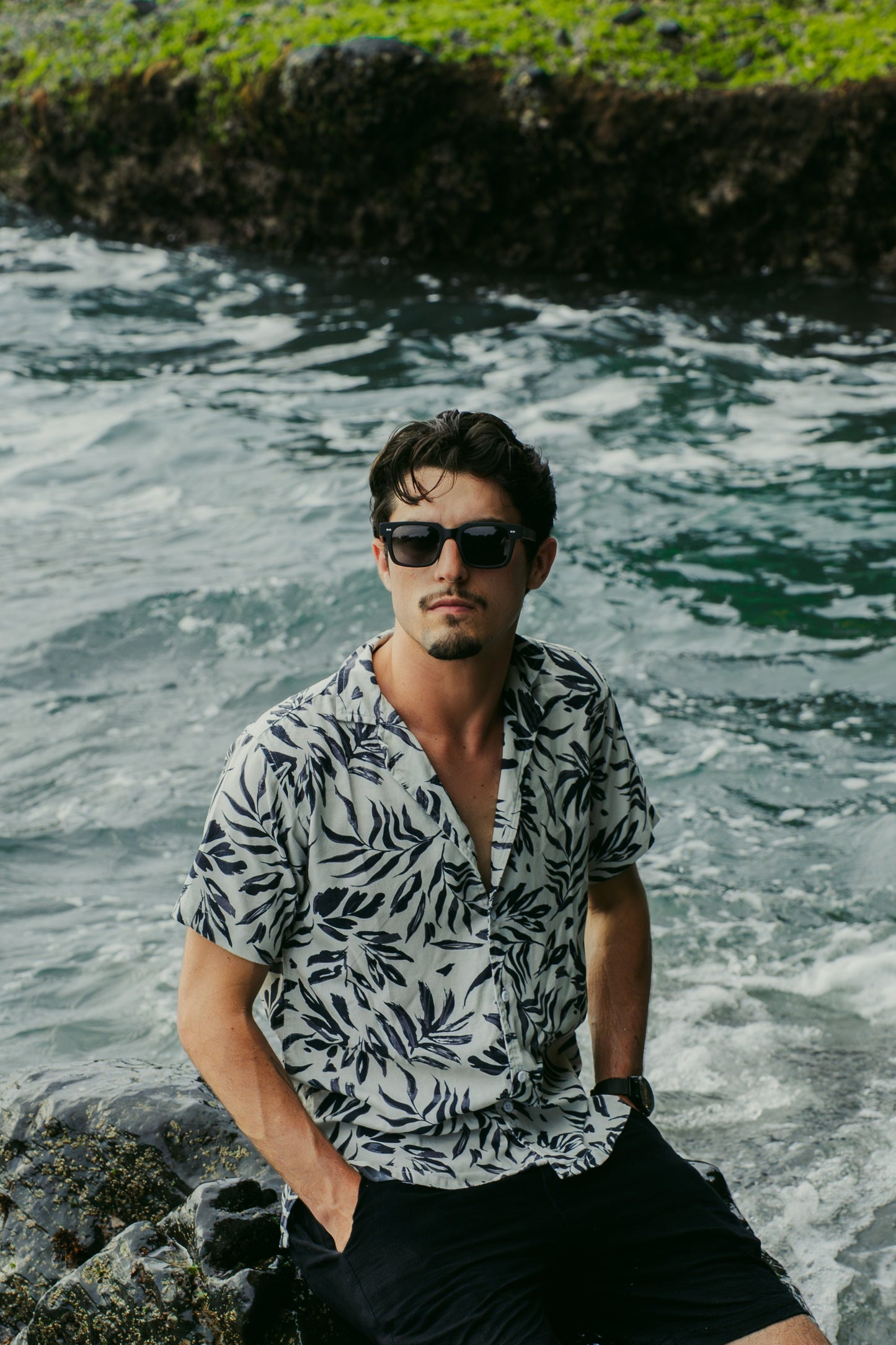 Man in Borneo Bliss Velvet Noir rectangular sunglasses under tropical foliage