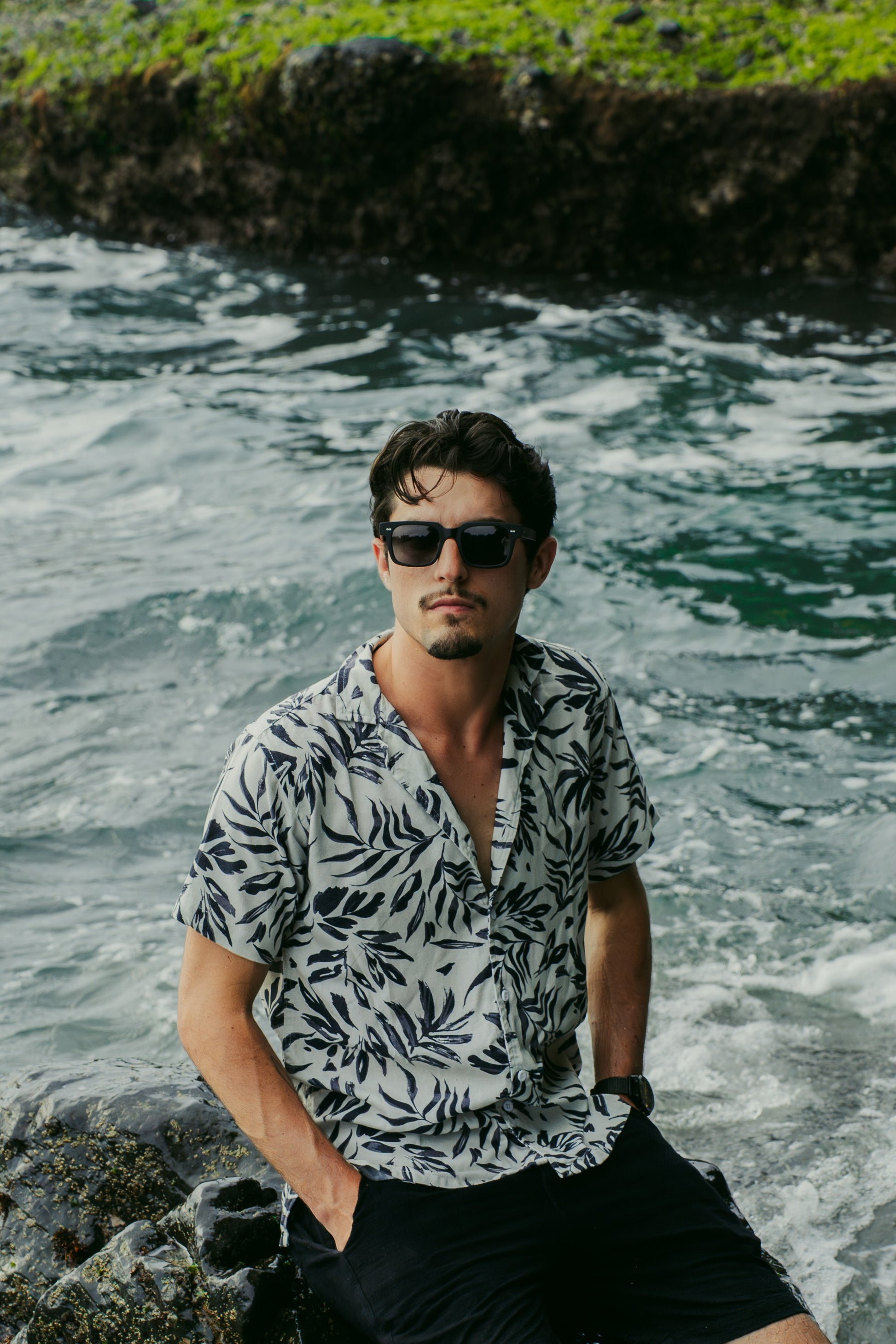 Man in Borneo Bliss Velvet Noir rectangular sunglasses under tropical foliage