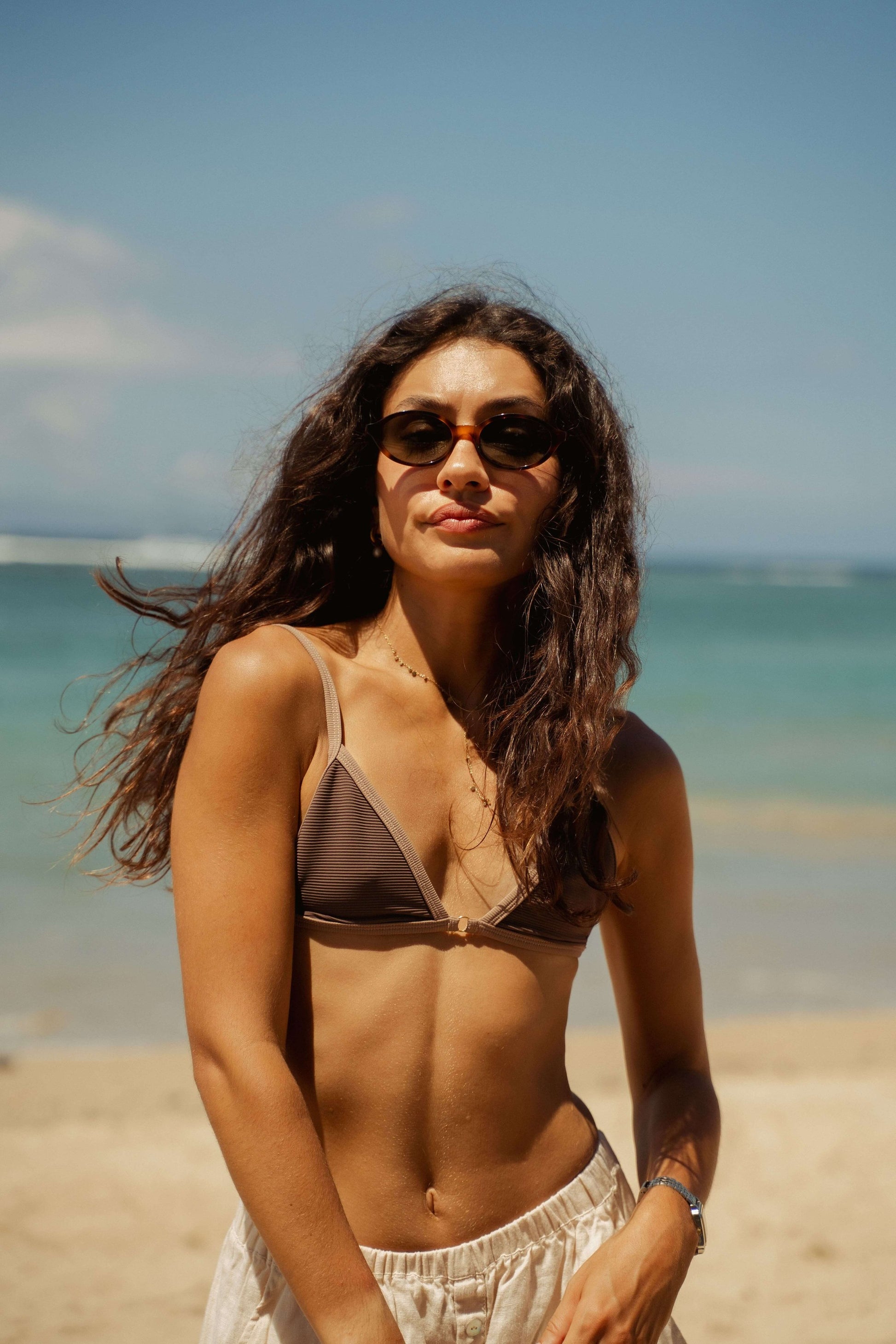 Portrait of woman in Cove Caramel Swirl tortoiseshell sunglasses by the sea in Bali