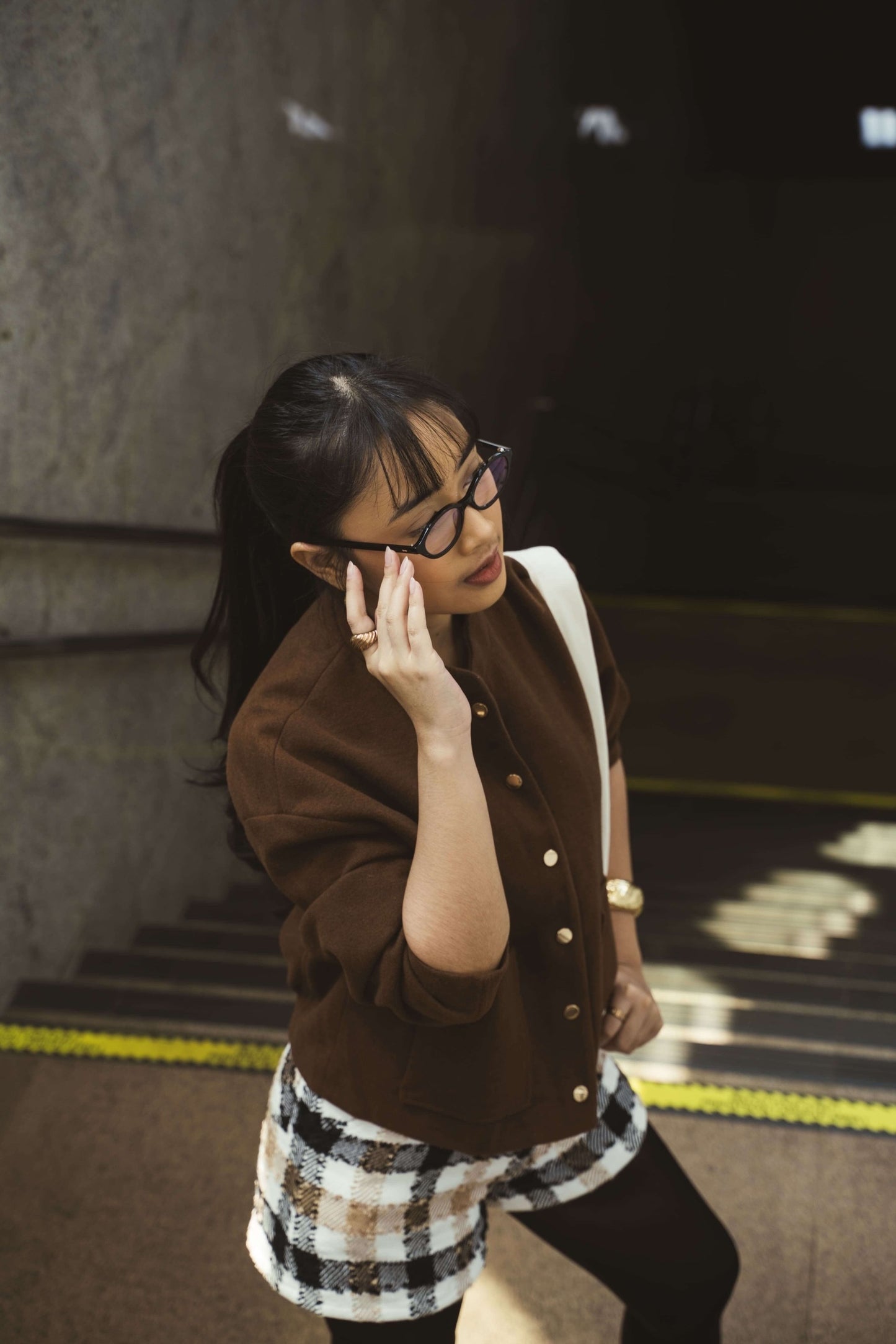 Woman in Cove Onyx Night oval eyeglasses and brown jacket in the city Maison Mata