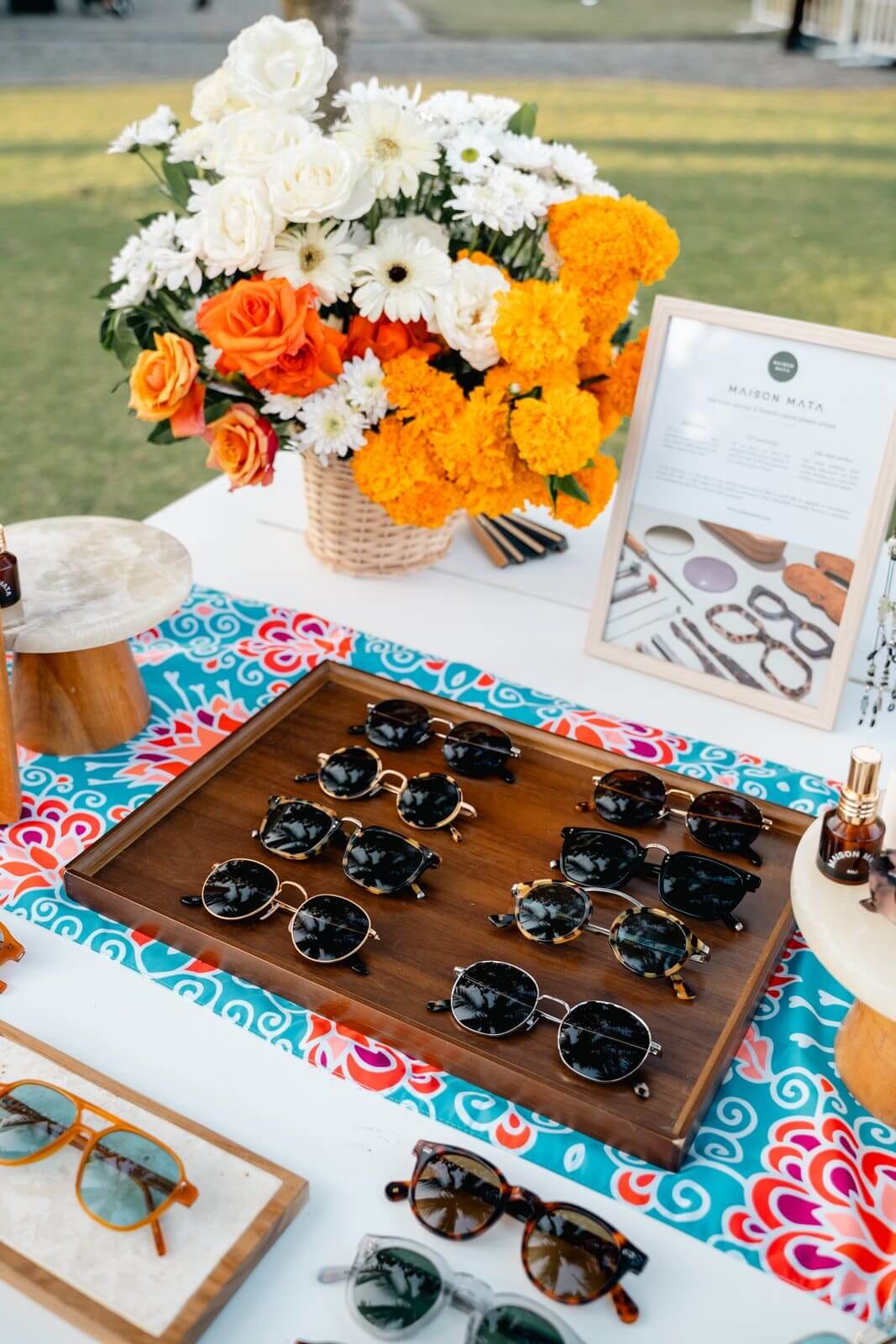 Maison Mata sunglasses displayed on wooden trays with fresh flowers at a corporate event in Bali