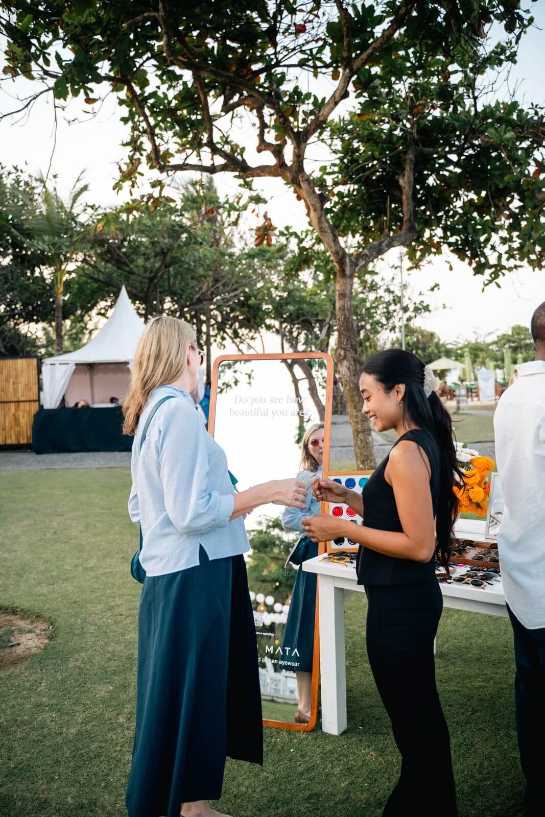 Maison Mata team helping a guest choose sunglasses at a beachfront event in Nusa Dua