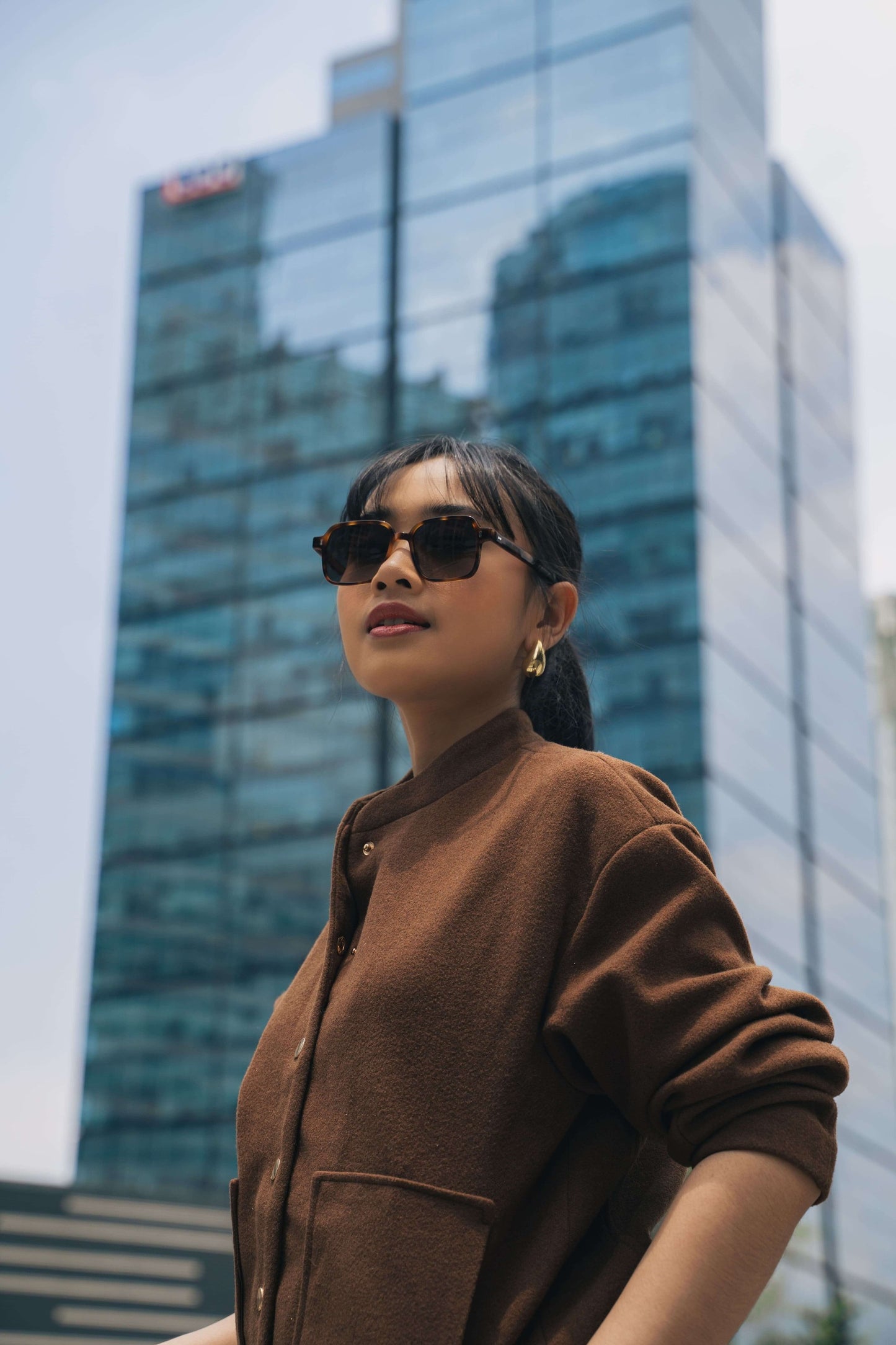 صورة لامرأة ترتدي نظارة شمسية مربعة جريئة Gili Escape بلون Caramel Swirl من Maison Mata.