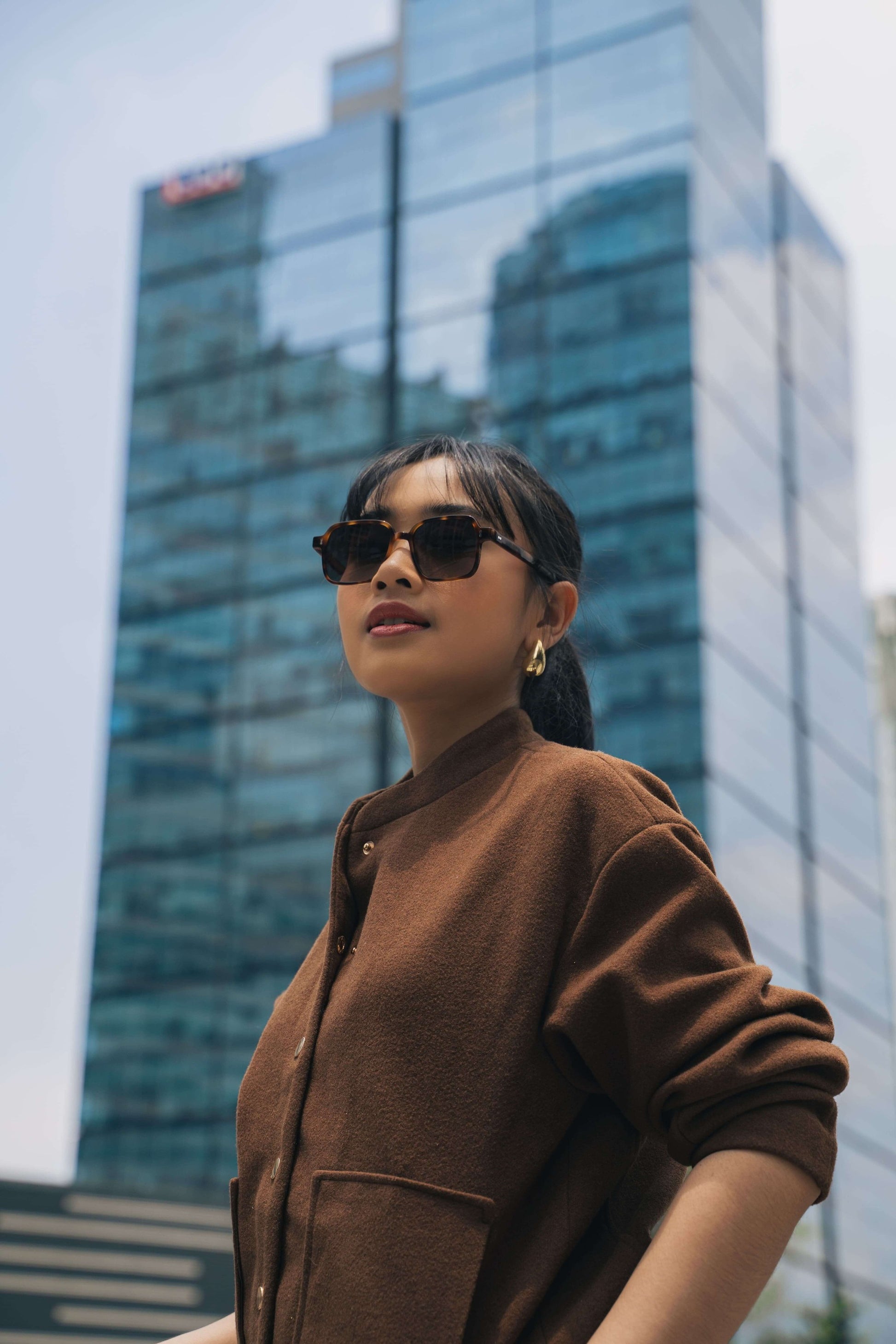 صورة لامرأة ترتدي نظارة شمسية مربعة جريئة Gili Escape بلون Caramel Swirl من Maison Mata.