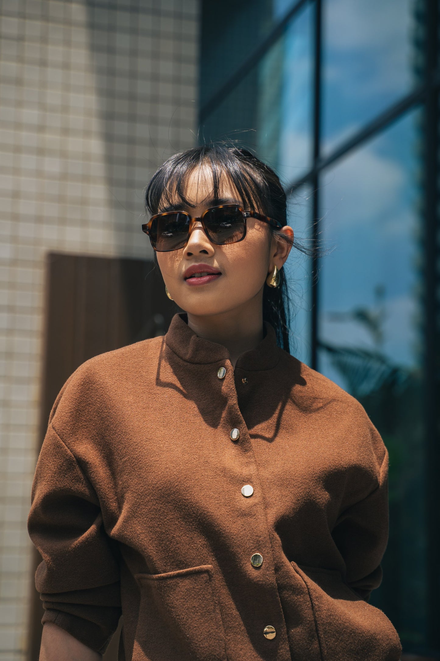 لقطة قريبة لامرأة ترتدي نظارة شمسية مربعة Gili Escape بلون Caramel Swirl بنقش صدفة السلحفاة.