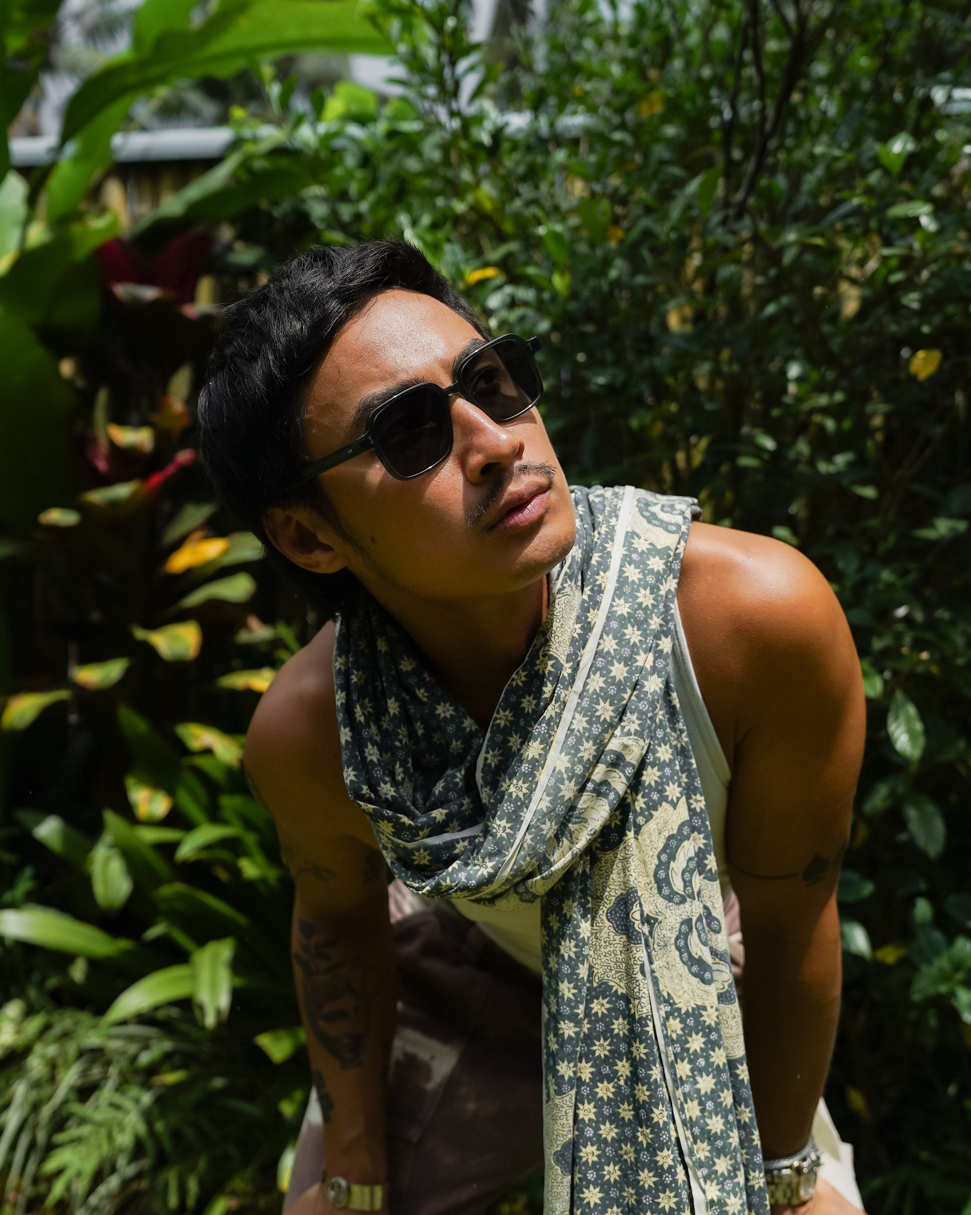 Man in Gili Escape Olive Gove sunglasses and printed scarf in a Bali garden