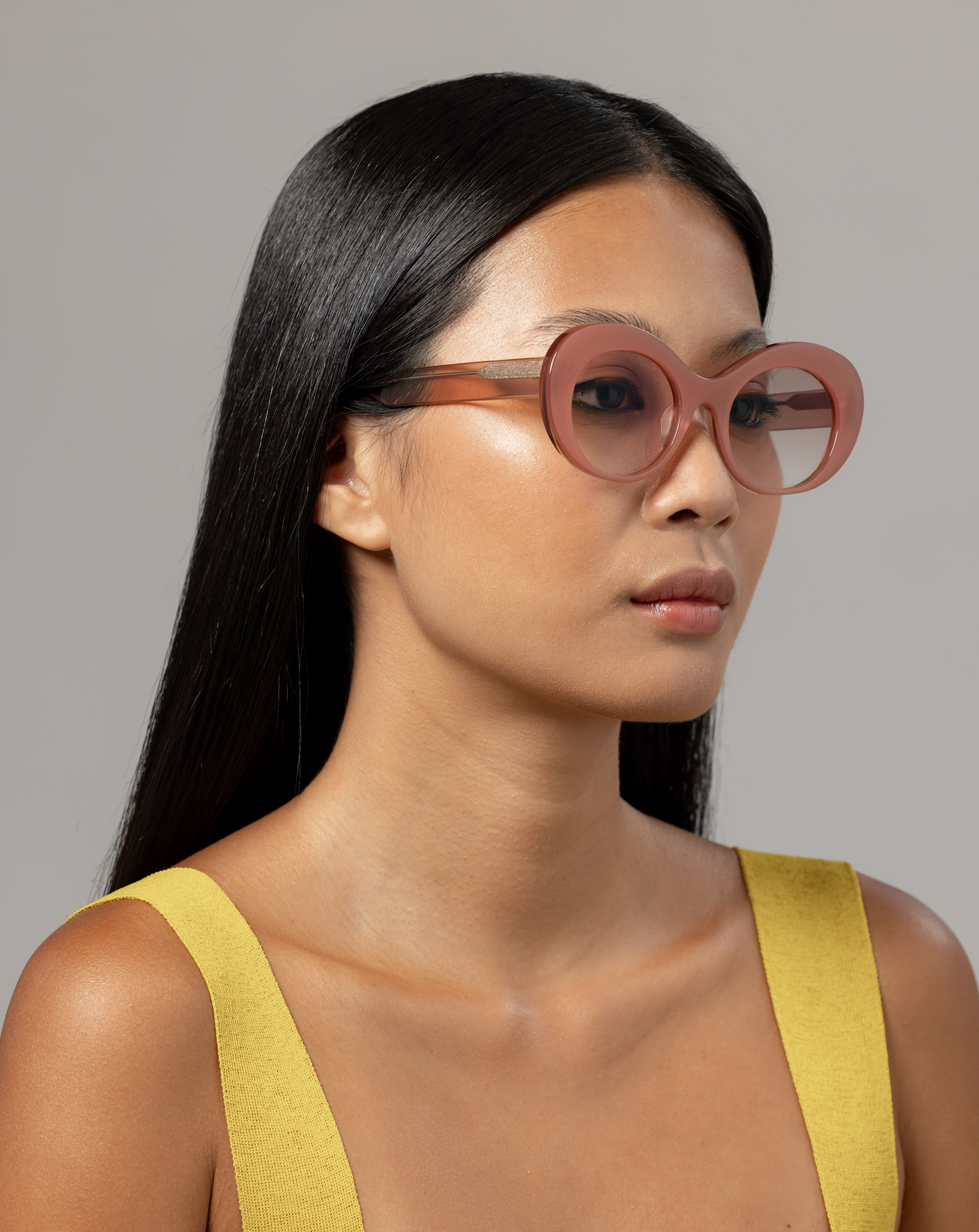 Woman wearing light-tinted pink sunglasses in a Bali villa, fitted with acetate frames by Maison Mata opticians.