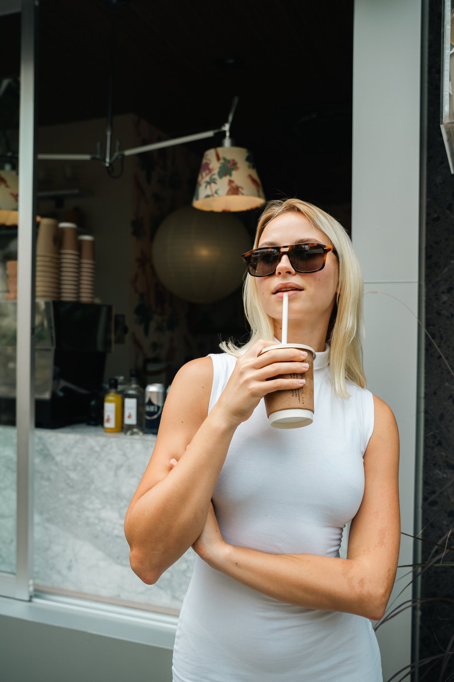 Woman in Java Joy Caramel Swirl aviator sunglasses at a Bali coffee window
