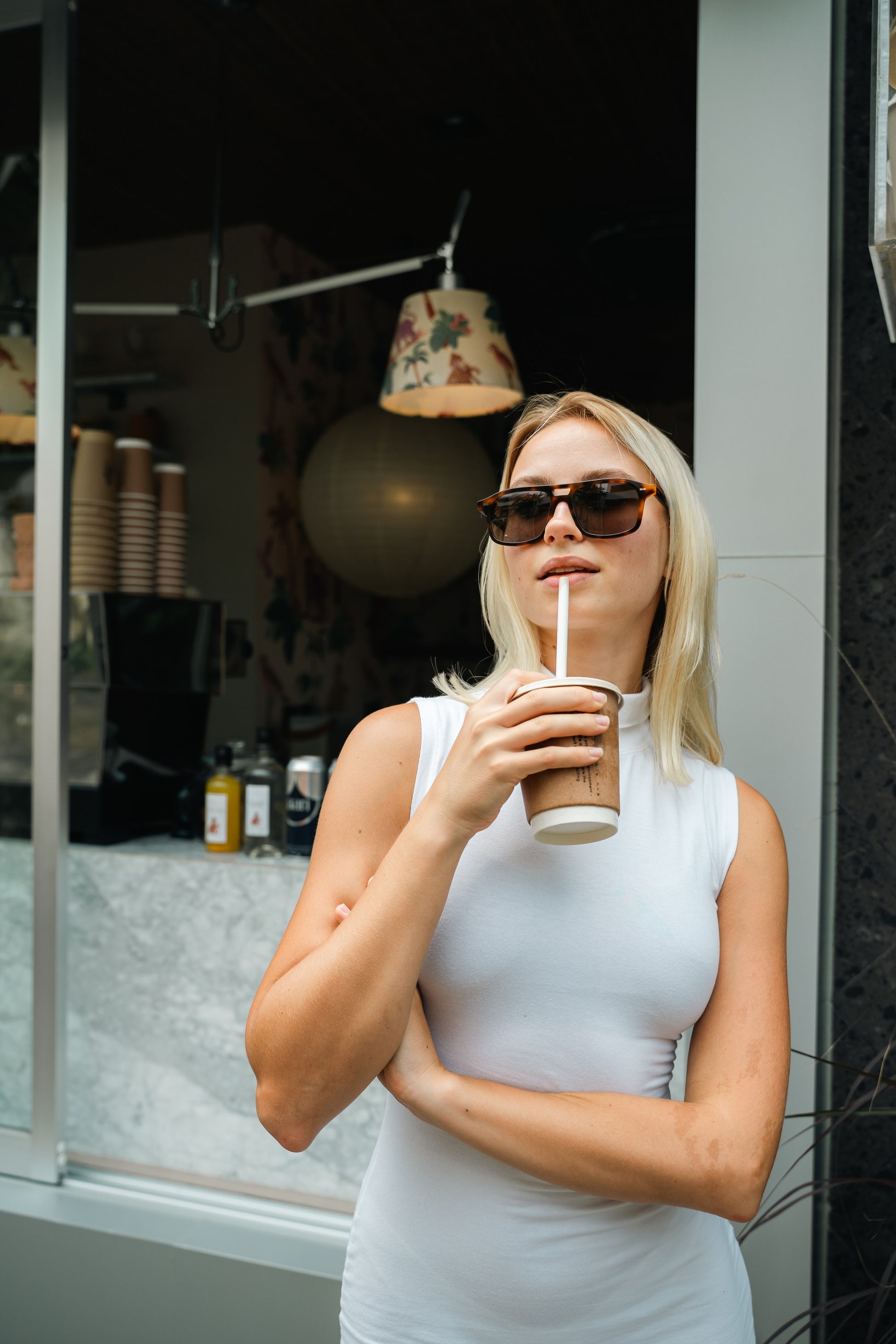 Woman in Java Joy Caramel Swirl aviator sunglasses at a Bali coffee window