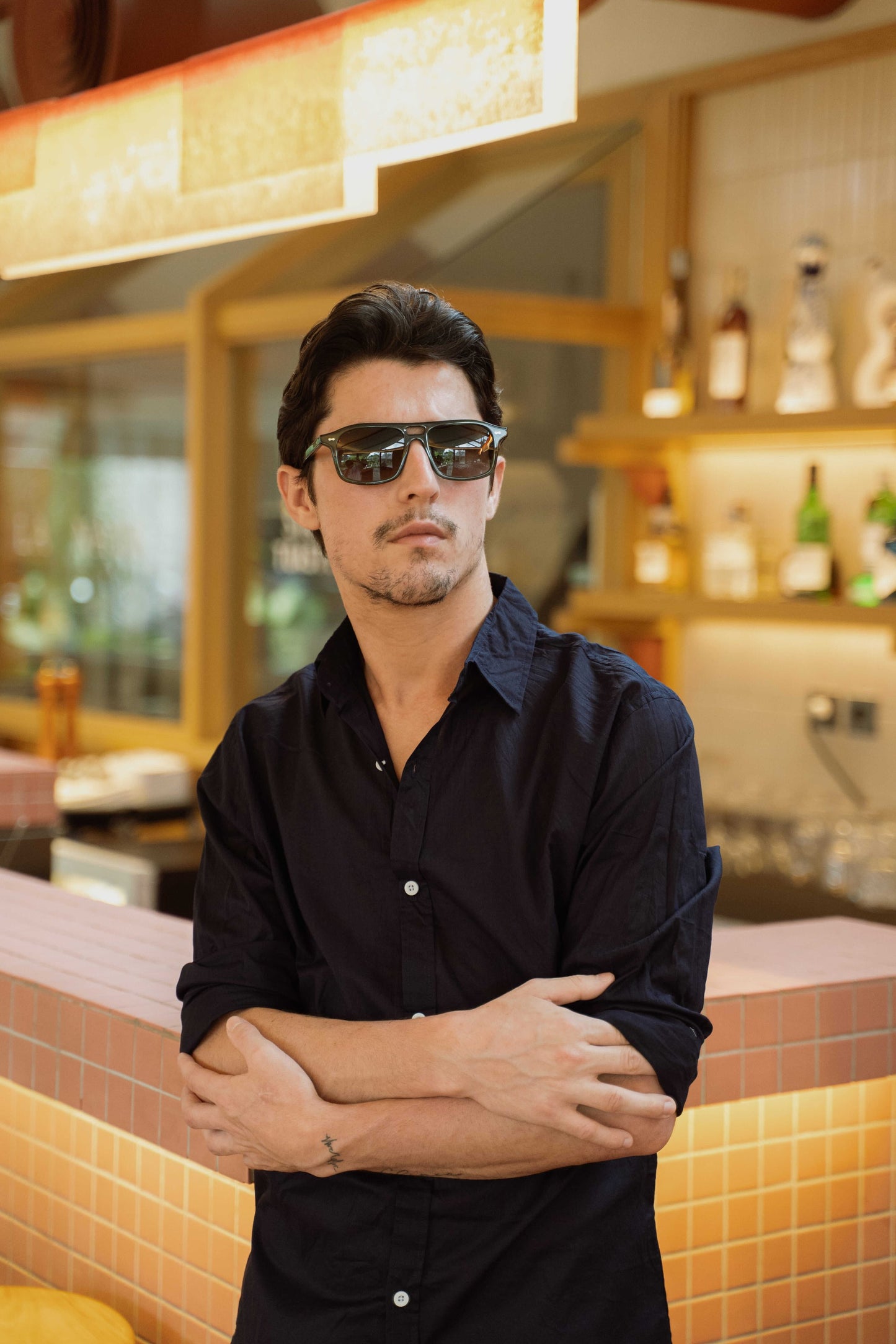 Man in Java Joy Olive Gove rectangular aviator sunglasses at a Bali bar Maison Mata