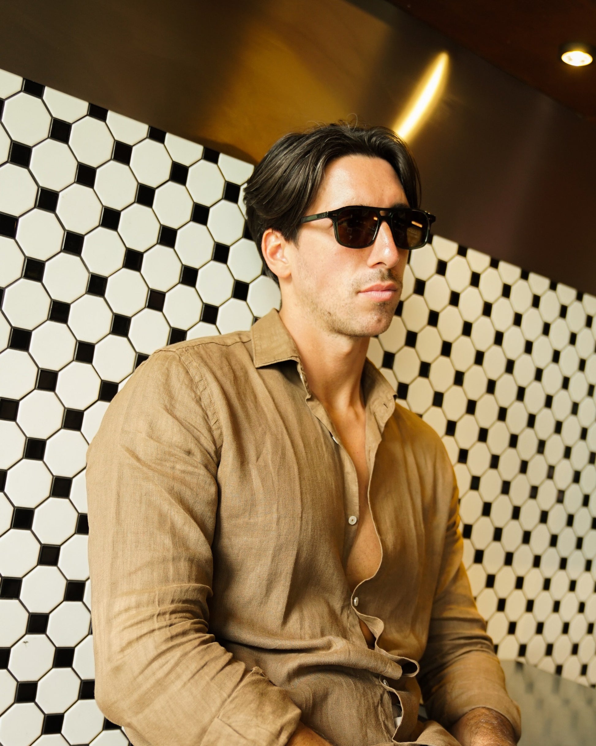 Man in Java Joy Olive Gove aviator sunglasses against a tiled wall in Bali