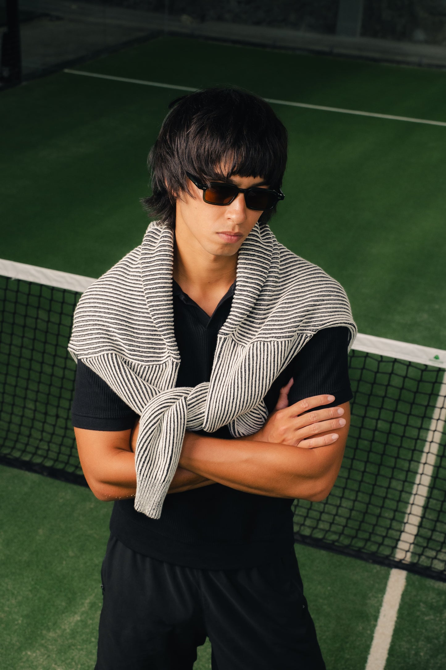 Man wearing Komodo Rise Olive Gove acetate and rectangular sunglasses with a knit over his shoulders in Bali