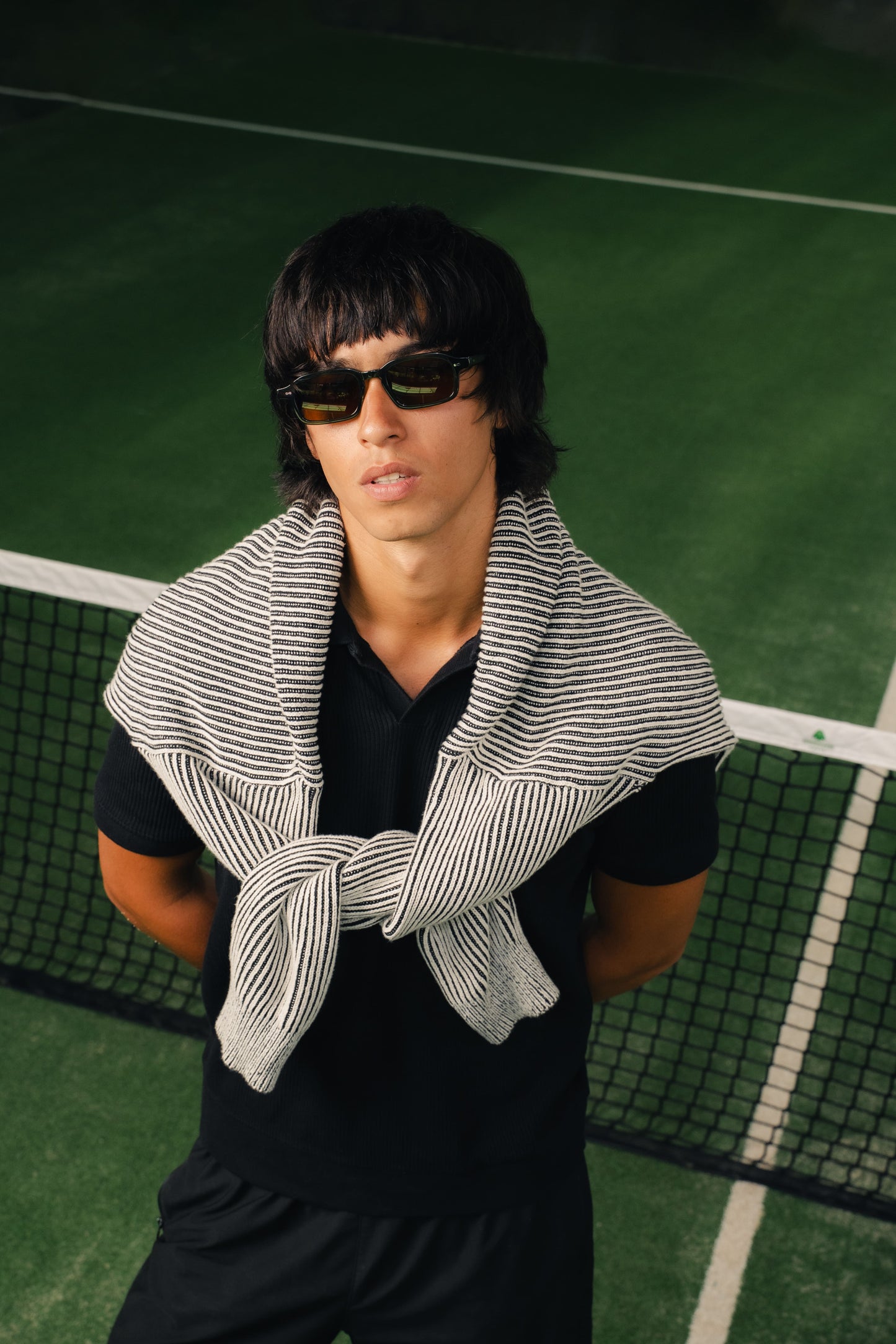 Man in Komodo Rise Olive Gove rectangular sunglasses on a tennis court in Bali Maison Mata