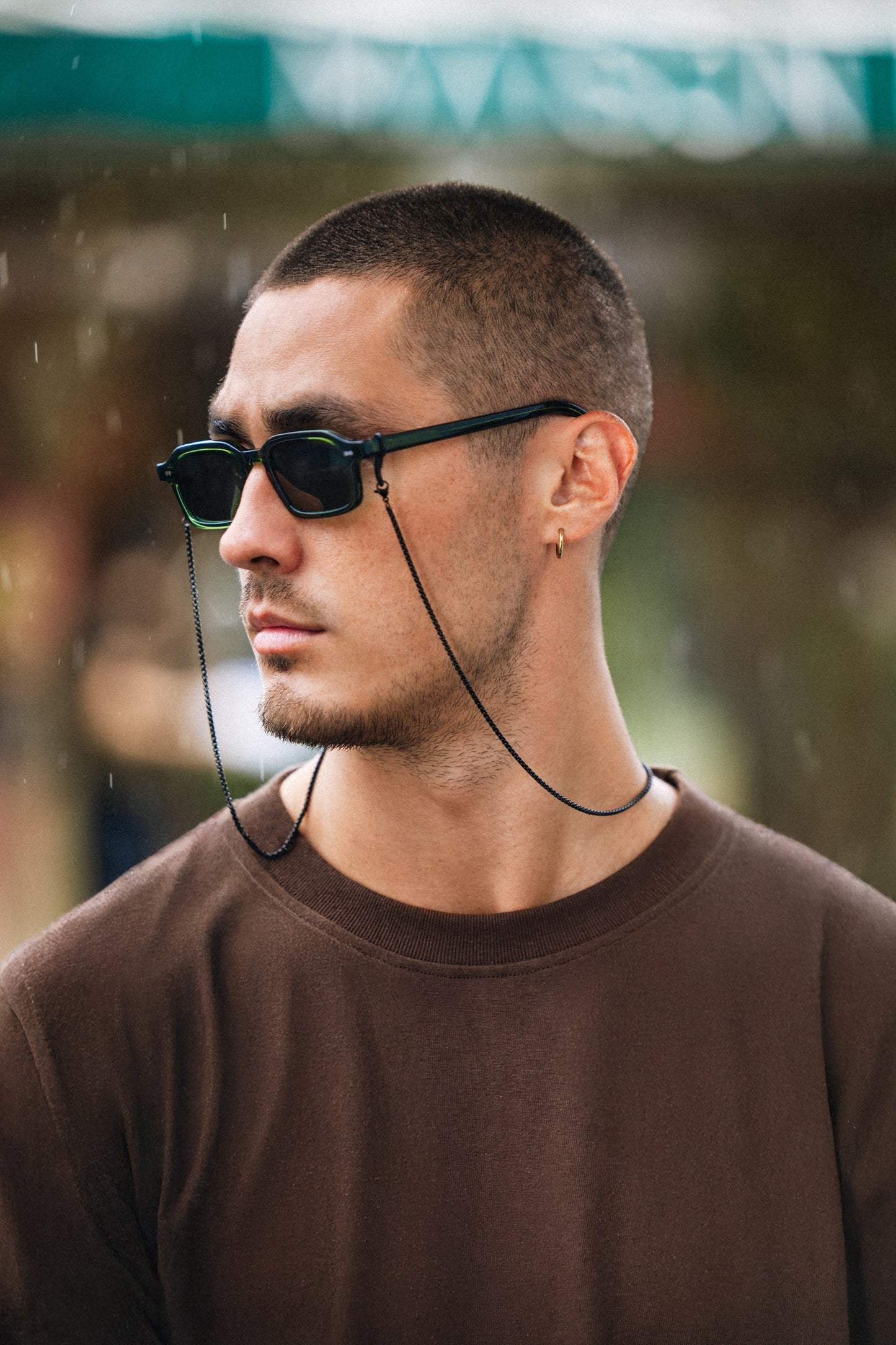 Man wearing Komodo Rise Olive Gove rectangular sunglasses with an eyewear chain