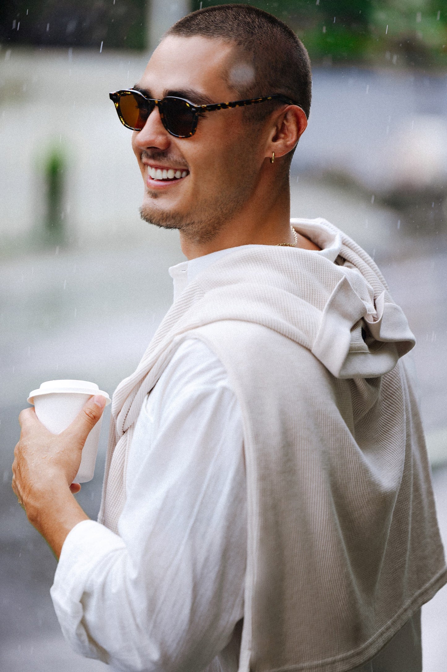 Man in Sumba Hills Black Sun softly squared sunglasses holding a coffee cup