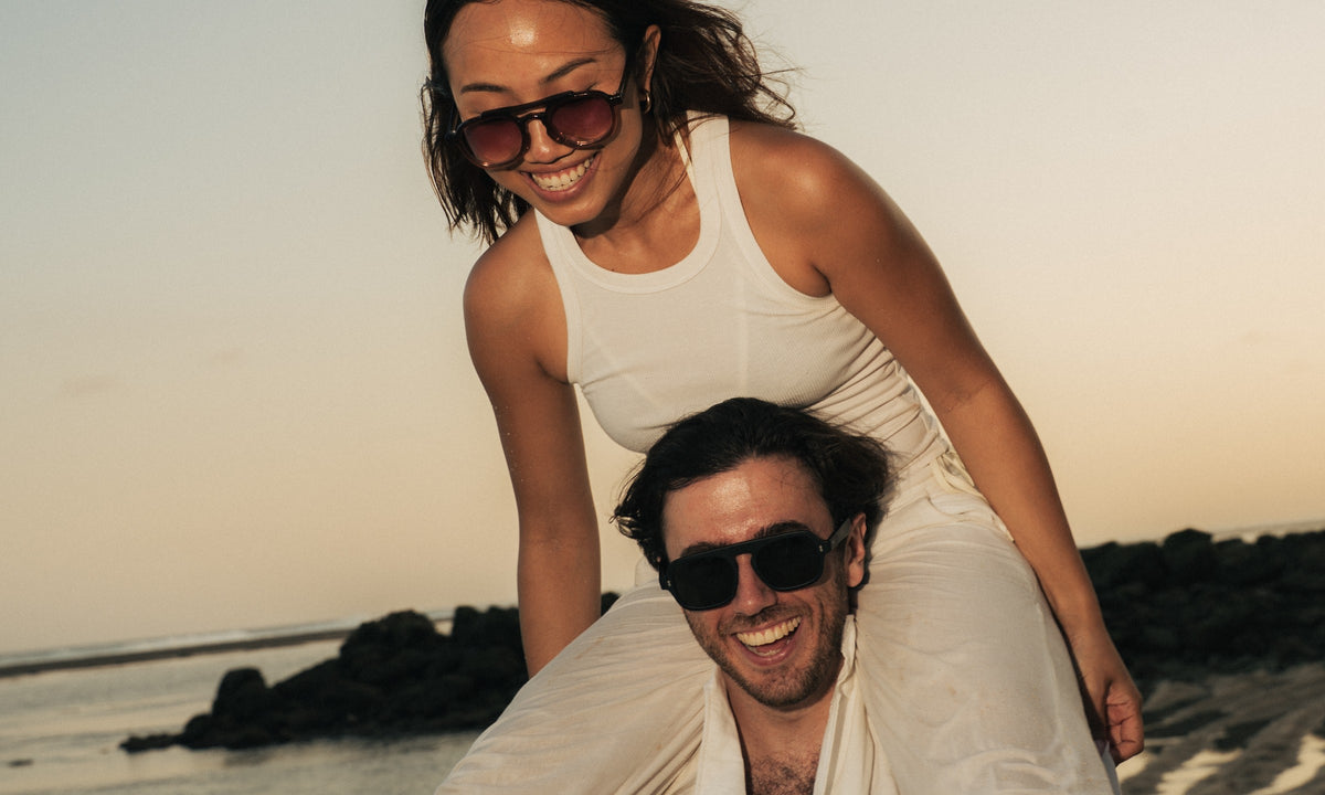 Couple on a Bali beach at sunset wearing Maison Mata sunglasses handmade in our Bali workshop