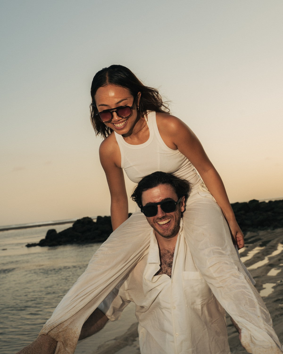 Couple on a Bali beach at sunset wearing Maison Mata sunglasses handmade in our Bali workshop